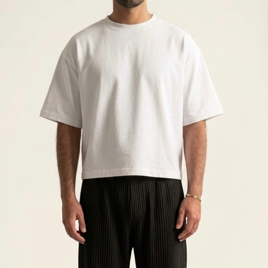 Person wearing a plain white t-shirt and black pleated pants on a light background