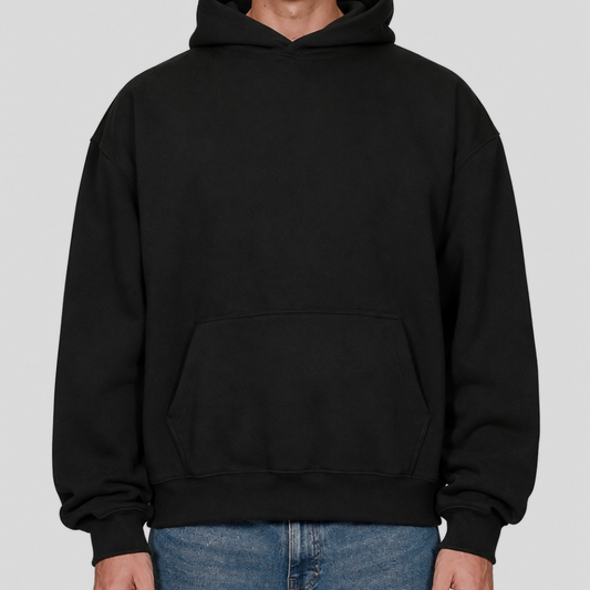 Model wearing a black blank hoodie with blue jeans, front view